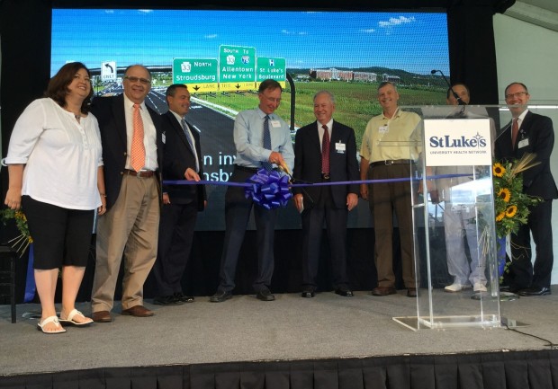 Bob Martin, St. Luke's Senior Vice President of Network Development, cuts the ribbon at a ceremony celebrating improvements to Freemansburg Avenue, as seen in a photo behind the stage.